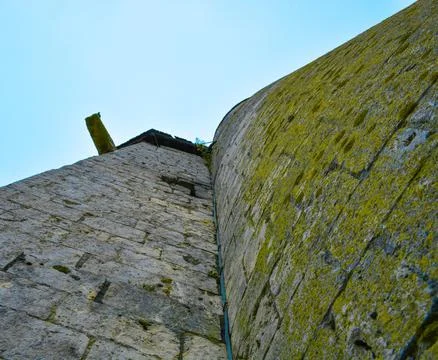 Low angle shot of an old building stone wall with moss in Paris, France under bl Stock Photos