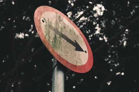 Low angle shot of an old, dirty arrow road sign Foto stock