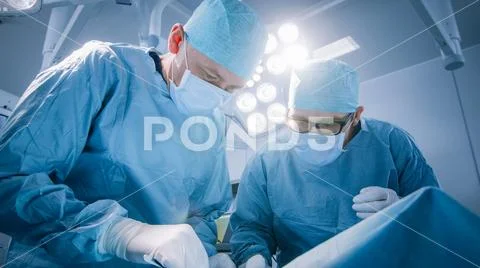 Low Angle Shot In Operating Room of Two Surgeons During the Surgery Procedure Stock Photos
