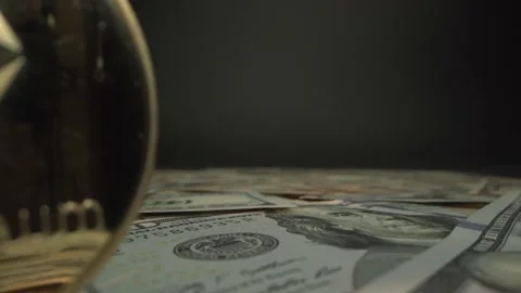 Low angle shot over 100 US dollar bills and gold crypto coin Etherium from Laowa Video stock 132484963