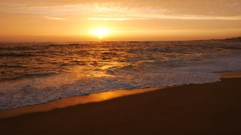 Low angle shot over beach at sunset with vivid orange sky and reflections Stock Footage 111168919