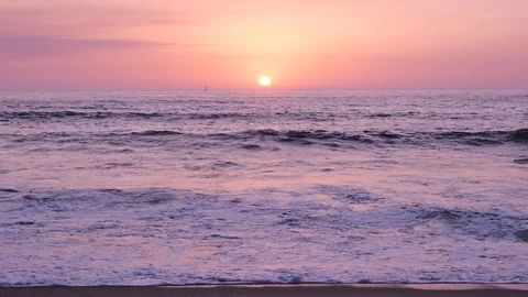 Low angle shot over ocean at sunset with sailing yacht in distance on horizon Stock Footage 115921180