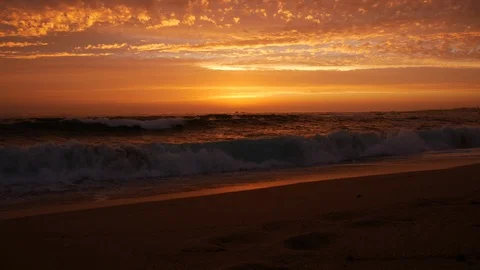 Low angle shot over shoreline on beach ut sunset with vivid orange sky Stock Footage 111167823