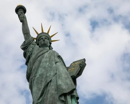 A low angle shot of the Paris Statue of Liberty captured under the cloudy sky Stock Photos