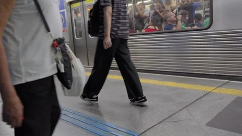 Low angle shot of passengers walking on a subway platform next to a train  Video stock 338185386