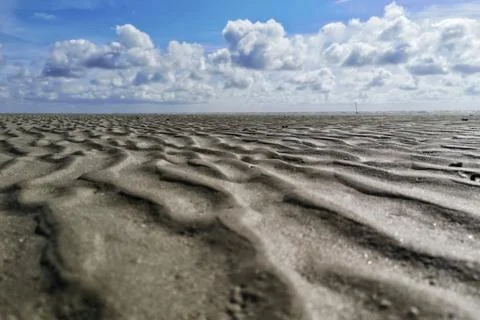 A low angle shot of the patterns on the wet sands on the beach under the beau Stock Photos