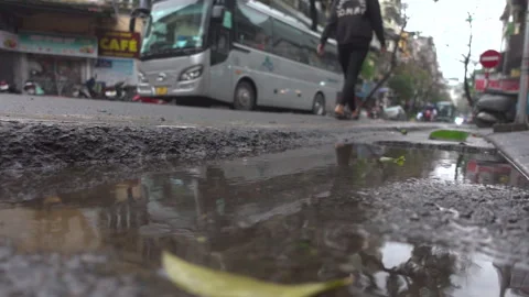 Low angle shot of pedestrian walking past a puddle of water Stock Footage 272284731