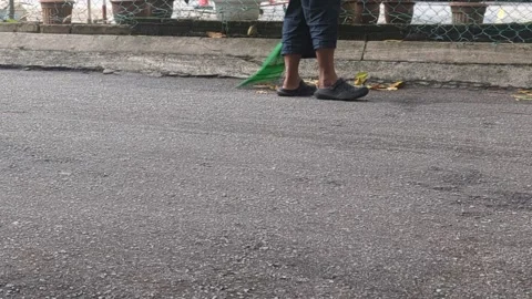 Low Angle Shot of Person Sweeping Asphalt Street with Traditional Broom Stock Footage 330574395