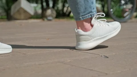 Low angle shot of a person wearing casual clothes and white running sneaker.. Vidéo 339861449