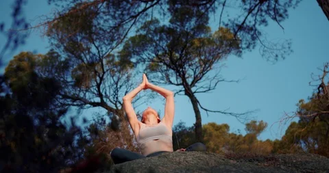 Low angle shot of pleasant female sitting in lotus pose lowering connected palms Stock Footage 120945959
