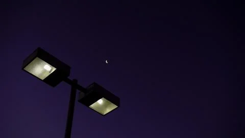 Low angle shot of post light with a tiny moon in the background Foto stock