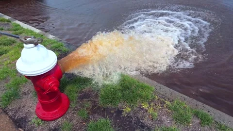 A low angle shot of a red and white fire hydrant spraying rusty water onto Vidéo 276203184