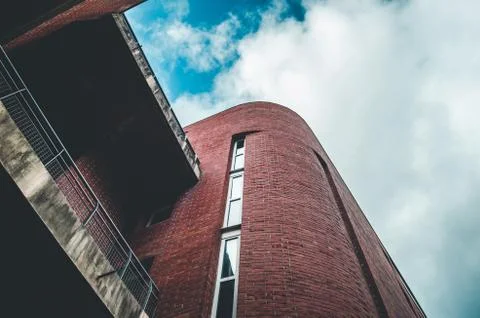 Low angle shot of red brick abstract architectural building under a cloudy sk 스톡 사진