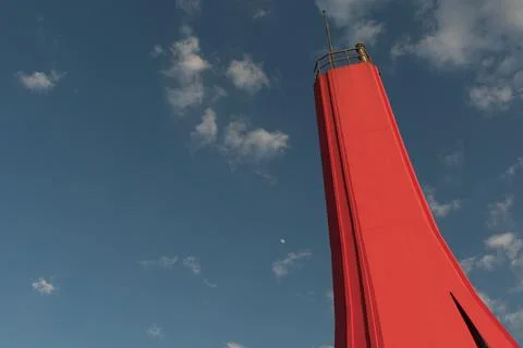 Low angle shot of a red lighthouse under a blue sky with tiny clouds Foto stock
