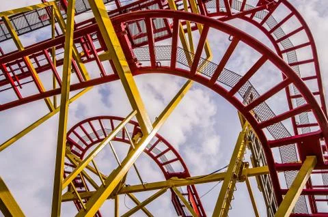 Low angle shot of a roller coaster ride with a cloudy sky in the background Stock Photos