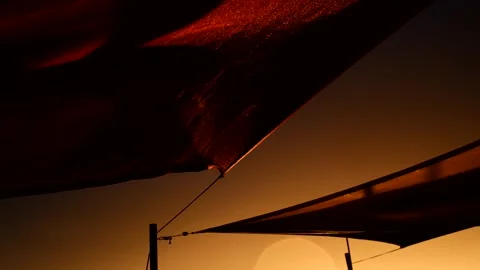 Low angle shot of sails blowing in stormy wind on waterfront at sunset Stock Footage 245948705