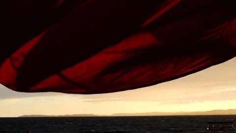 Low angle shot of sails blowing in stormy wind on waterfront at sunset Stock Footage 245948748