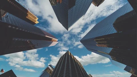 A low-angle shot of several modern skyscrapers against a vibrant blue sky dotted Stock Footage 306745894