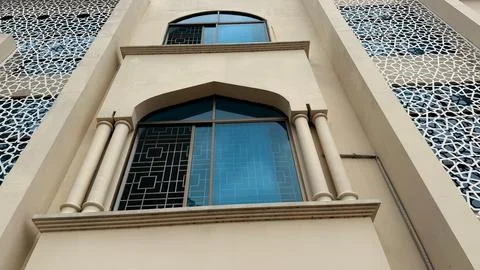 Low-angle shot showcasing a beige building with arched windows, supported by  Foto stock