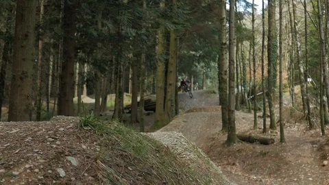 Low angle shot showing a mountain biker riding over 3 large jumps. Biker Stock Footage 108128410