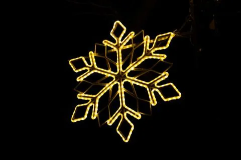 Low angle shot of a snowflake made with lights at night time Foto stock