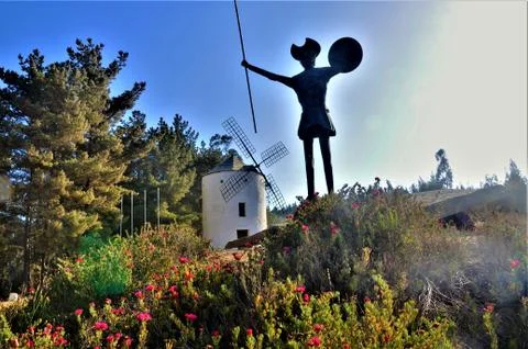 Low angle shot of a statue next to a windmill on a hill under the clear sky Foto stock