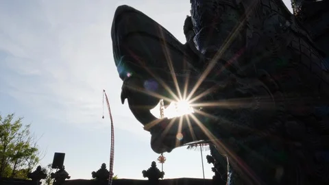 Low angle shot of sun shining through hindu statue in front of a temple, Bali Stock Footage 140258774