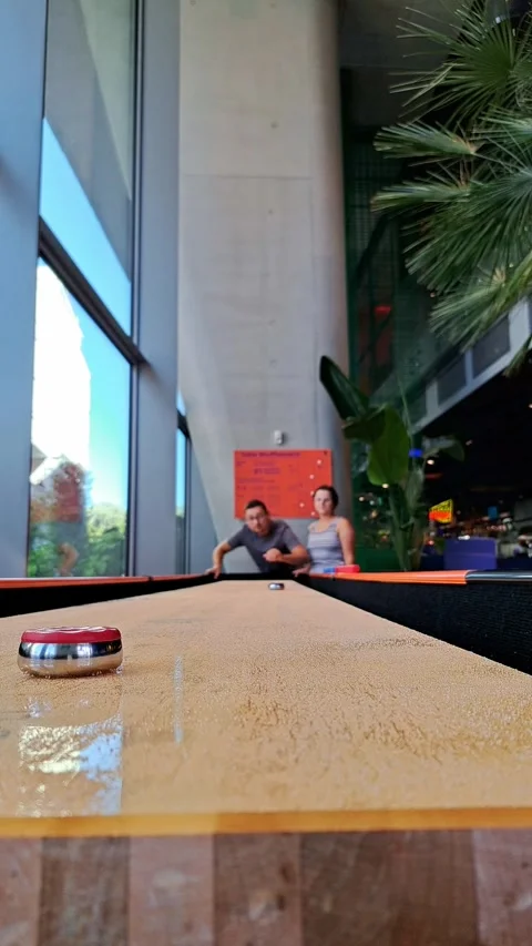 A low-angle shot of a table shuffleboard game with shiny pucks on a long wo.. Stock Footage 336982266