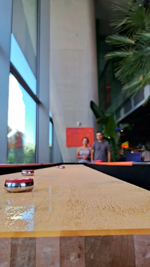 A low-angle shot of a table shuffleboard game with shiny pucks on a long wo.. Stock Footage 336982269