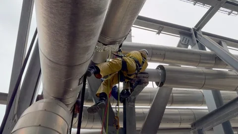 Low angle shot of technician repairing a plant in an oil or chemical refinery Stock Footage 334846601