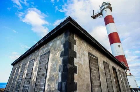 Low angle shot of a tiny building with a lighthouse in the background Foto stock
