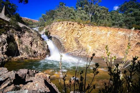 Low angle shot of a tiny waterfall foaming and making a rainbow in a pond Stock Photos