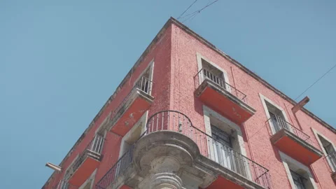Low angle shot of traditional pink building facade with wrought iron balconies Видео 346328069