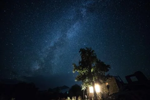 Low angle shot of a tree and an old house under the beautiful starry night sk Stock Photos