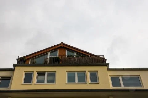 A low-angle shot of a triangular mansard brick roof with a balcony against a  스톡 사진