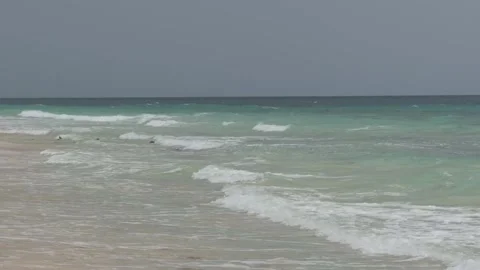 A low angle shot of turquoise ocean water and gentle foam waves rolling onto a Stock Footage 341562049