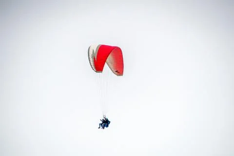 Low angle shot of two people paragliding in the cloudy sky Fotos de archivo