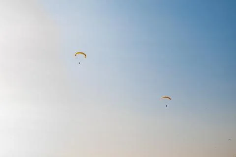 Low angle shot of two people paragliding on a blue sky background Foto stock