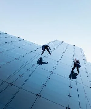 Low angle shot of two persons rappelling at the side of a tall building Fotos de archivo