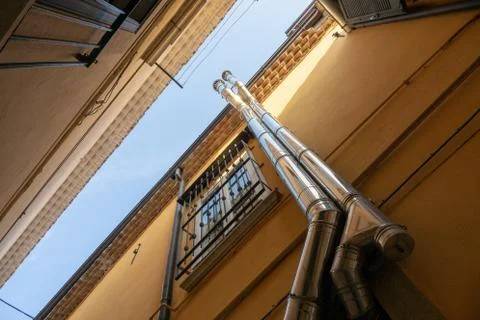 Low angle shot of two pipes as they go up the building next to a window Stock Photos