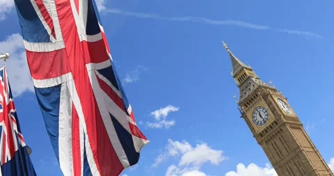 Low-angle shot of the Union Jack flag blowing in the wind beside Big Ben Stock Footage 319792878