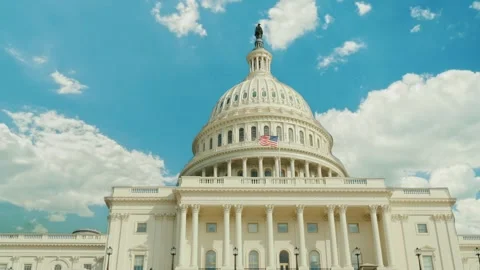 Low angle shot of United States Capitol building with American flag waving .. Stock Footage 334607270