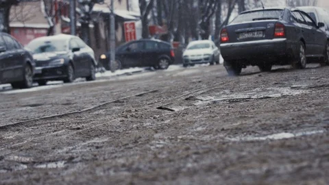 Low angle shot view of car wheel moments before hitting pothole on muddy sleet Stock Footage 104910160