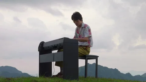 Low Angle Shot of Vintage Asian Male Musician Playing Piano on Mountain Peak Stock Footage 340399044