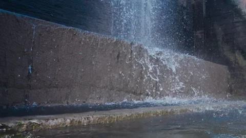 Low-angle shot of water splashing violently at the base of a concrete weir dam. Stock Footage 337768257