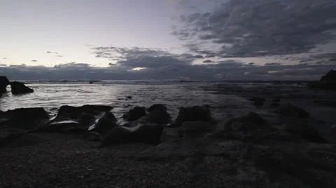 Low angle shot of waves breaking on a rocky shoreline during sunset Stock Footage 34134214