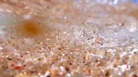 Low angle shot of waves crashing onto a sandy beach 스톡 동영상 328647290