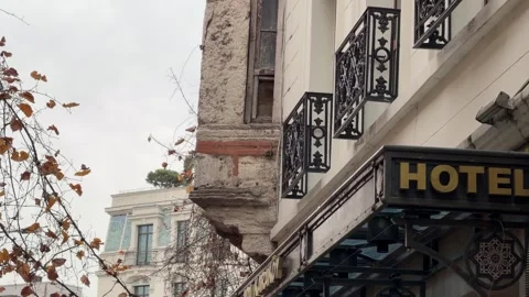Low angle shot weathered stone facade, wrought iron balconies, and hotel Vídeos de archivo 340155080