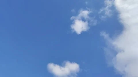 Low angle shot of white clouds moving across a bright blue sky on a sunny day. Stock Footage 334901188