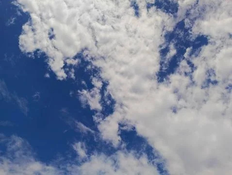 A low angle shot of white clouds floating across a clear blue sky. The clouds Stock Photos